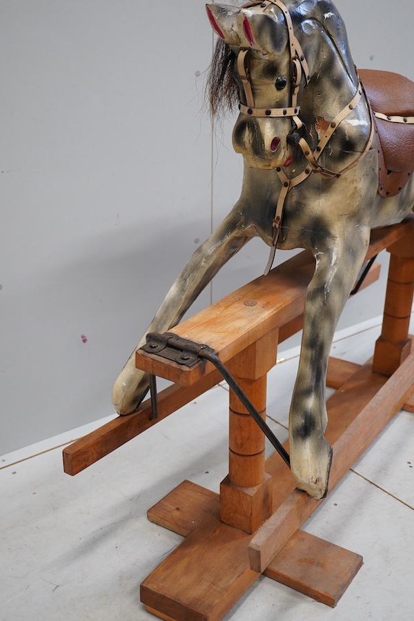 An early 20th century dapple grey rocking horse, on later trestle base, length 132cm. Condition - fair.